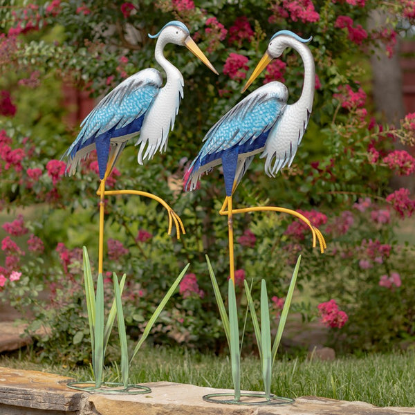 Our Blue and White Coastal Heron Garden Statuary comes as a set of 2. These metal blue heron coastal garden birds are crafted from high quality metal, powder coated for added protection against weatherization, and individually hand painted for a unique one-of-a-kind outdoor decoration. Each comes with its own freestanding cattails reed stand. They will enhance any front lawn, backyard, or bird garden with their magnificent blue and white finish and stunningly detailed bodies and feathers.
