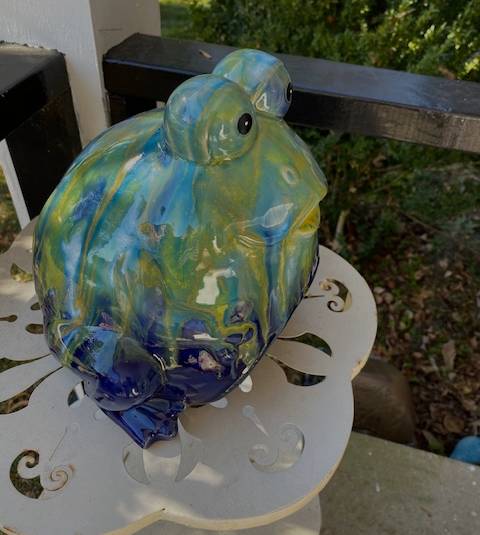 Side View of  Our Frivolous Frog Toad Abode Garden Statuary. This guy  is sure to make a splash in any garden! Each colorful ceramic creature has fascinatingly large eyes that draw you in and a unique marbling of blues, greens, yellows, and whites down its body.