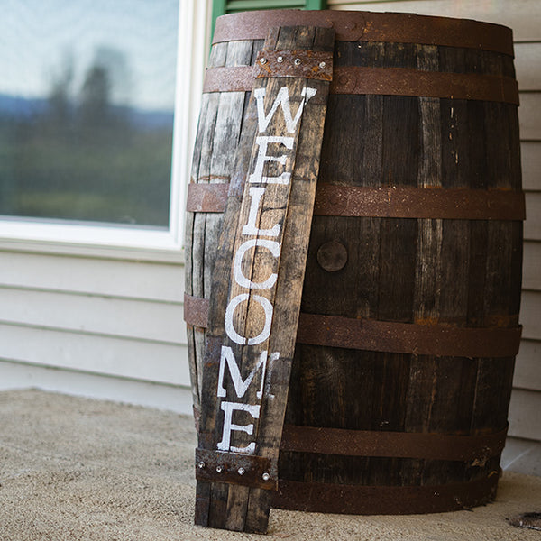 Our Reclaimed Whiskey Barrel Porch Welcome Sign, made in the USA, has been created from reclaimed and repurposed whiskey barrels, this piece has been created from a genuine wood stave from an aged whiskey barrel. Our porch welcome sign will certainly Invite and welcome guests to your home as well as add a bit of rustic charm and appeal to your guests coming up onto your porch. The word WELCOME has been hand stenciled in white onto the stave. Size is 6.5"W x 1"D x 34"H