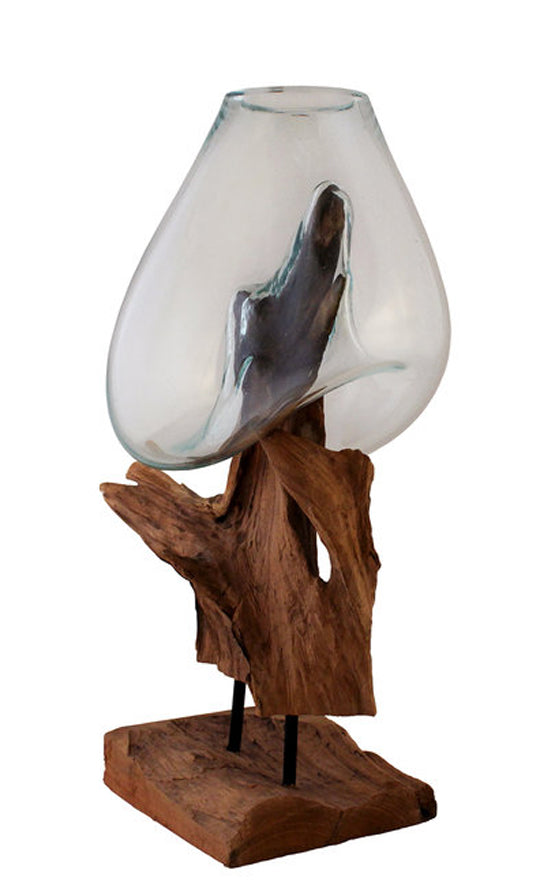 This 24” tall handblown glass and teak wood sculpture has been handcrafted by skilled artisans who have a love for the art of glass blowing. Recycled glass is blown onto the shape of the teak wood root and begins to flow and cradling the form of the wood to create a bowl that is a unique, one of a kind, piece that can be used as a vase, terrarium or fishbowl.