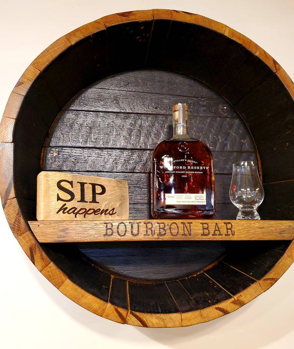 Our Reclaimed Whiskey Barrel Head Cabinet Shelf is made from retired whiskey barrels that have been distinctively repurposed into whiskey barrel head wall décor that has a rustic, vintage style that is unique and purposeful. The shelf portion can be personalized with your own creativity or you can use one of our 3 premade sayings. This custom made to order item ships in 2-3 weeks. It is 21” in diameter by 7” deep.  Show with engraving of BOURBON BAR