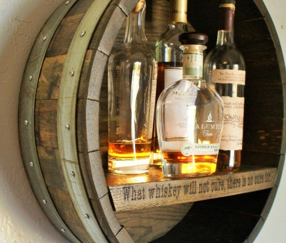Our Reclaimed Whiskey Barrel Head Cabinet Shelf is made from retired whiskey barrels that have been distinctively repurposed into whiskey barrel head wall décor that has a rustic, vintage style that is unique and purposeful. The shelf portion can be personalized with your own creativity or you can use one of our 3 premade sayings. This custom made to order item ships in 2-3 weeks. It is 21” in diameter by 7” deep.  Shown with engraving "What whiskey will not cure, there in no cure for."