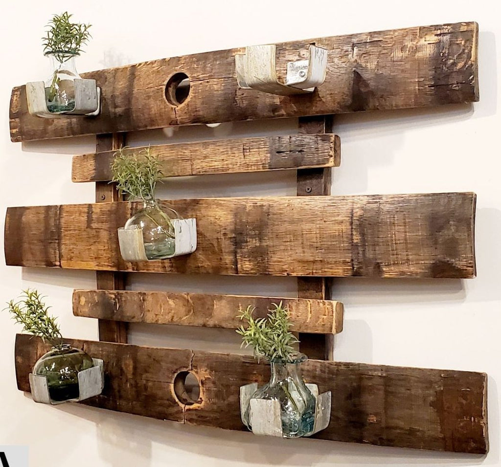 Our Reclaimed Whiskey Barrel Staves Wall Garden Planter / Candle Holder has been handcrafted in the USA by skilled artisans who have disassembled a reclaimed whiskey barrel and created a wall décor piece, preserving both the staves and barrel rings to create this beautiful wall accent. The staggered wood has five metal plant/candle holders which can accompany up to a 4” pot or 3.5” candle or bottle. 