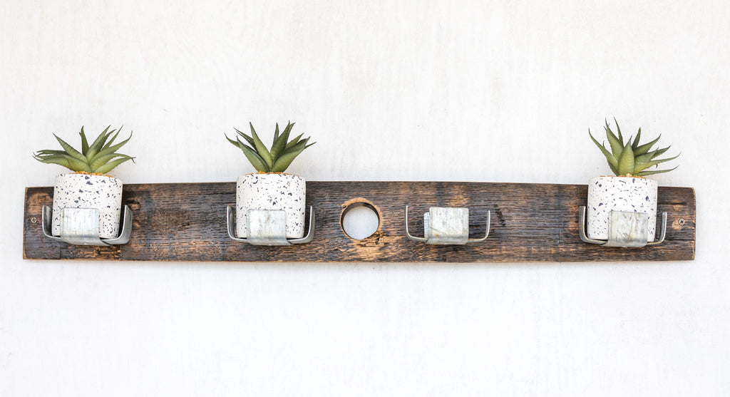  Our Reclaimed Whiskey Barrel Staves Wall Planter is a unique creation for growing plants indoors and outdoors. Made in the USA by skilled artisans who have disassembled a whiskey barrel and using the staves, they have made them into a wall décor piece that can be mounted vertically or horizontally and then added the original metal whiskey barrel rings to create four plant holders. Shown in our 4 cup plant holder in horizontal position.