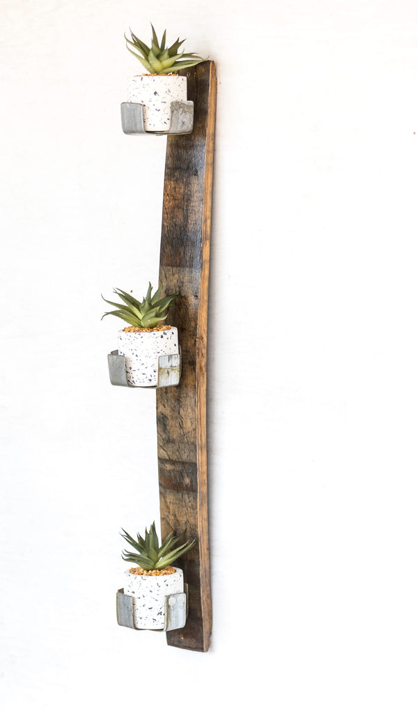  Our Reclaimed Whiskey Barrel Staves Wall Planter is a unique creation for growing plants indoors and outdoors. Made in the USA by skilled artisans who have disassembled a whiskey barrel and using the staves, they have made them into a wall décor piece that can be mounted vertically or horizontally and then added the original metal whiskey barrel rings to create four plant holders. Shown with our 3 cup planter in a vertical position.