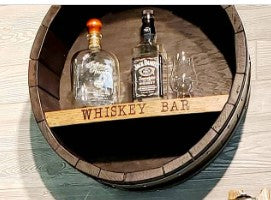 Our Reclaimed Whiskey Barrel Head Cabinet Shelf is made from retired whiskey barrels that have been distinctively repurposed into whiskey barrel head wall décor that has a rustic, vintage style that is unique and purposeful. The shelf portion can be personalized with your own creativity or you can use one of our 3 premade sayings. This custom made to order item ships in 2-3 weeks. It is 21” in diameter by 7” deep.  Show with engraving of WHISKEY BAR