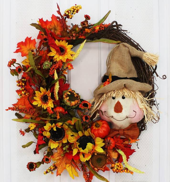 Handcrafted here in the USA, our Scarecrow and Sunflowers Fall Grapevine Front Door Wreath is 24 inches in diameter and features a stunning array of fall colors with a side exposed grapevine wreath that has been wrapped with an assortment of eye catching orange leaves, wispy greenery, berries, sunflowers, pumpkins and the most adorable scarecrow ever!.